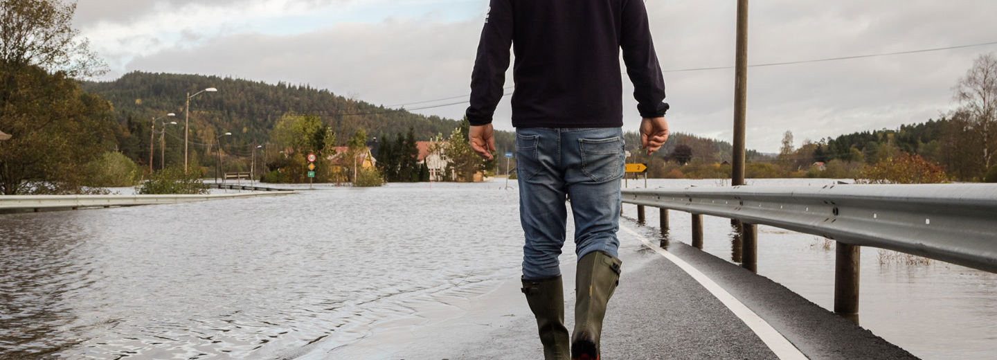 Væromslaget som kommer kan gi oversvømte gater. Mann går i oversvømte gater.